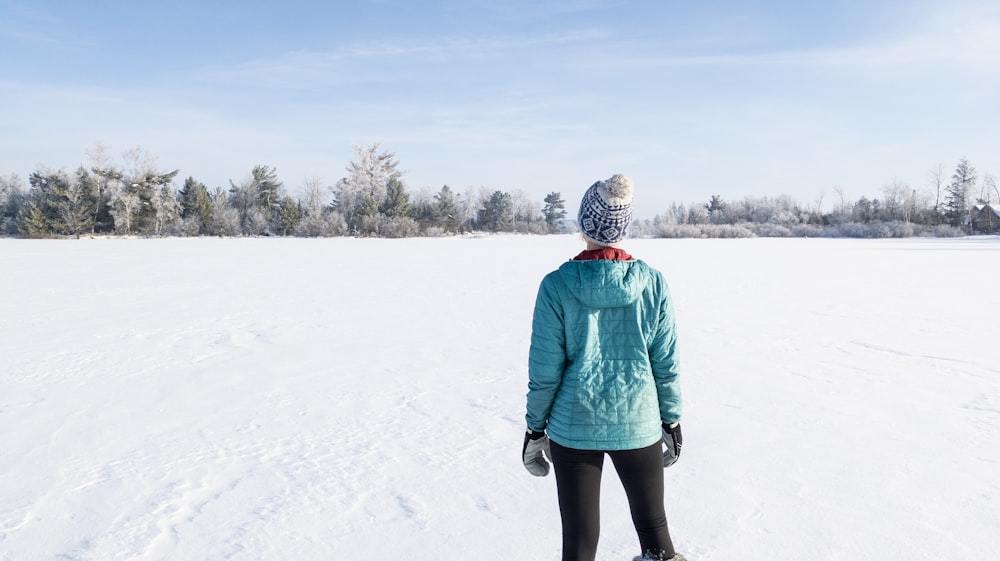 person in green jacket standing on snow covered ground during daytime