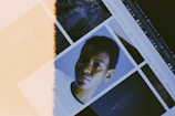 A computer screen displays a collage of images, including one of a person looking directly at the camera. The display has a noticeable light leak effect, creating a vintage or artistic appearance.