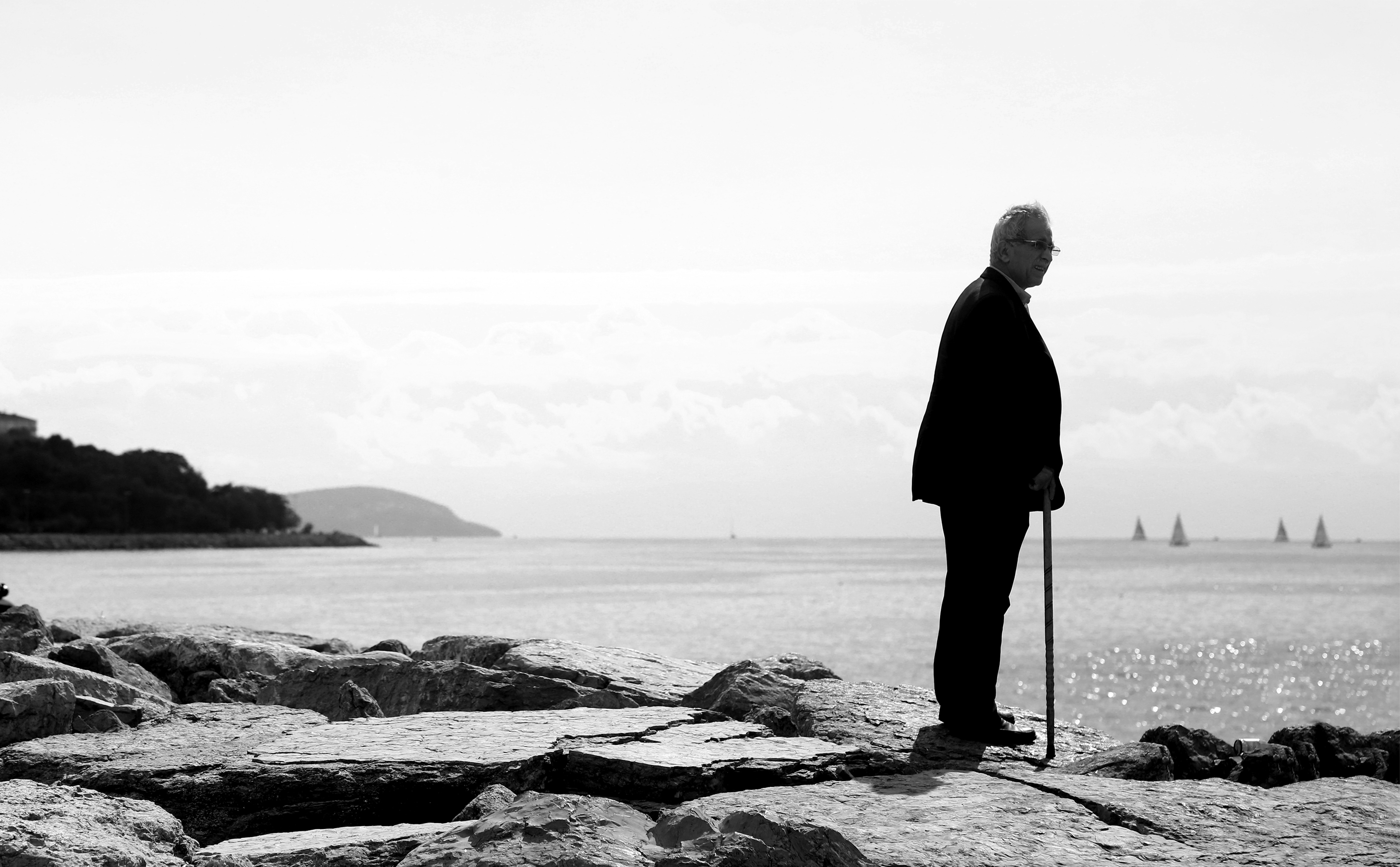 man in black coat standing on rocky shore