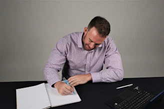 A researcher cross-checking multiple sources with notes and a laptop.