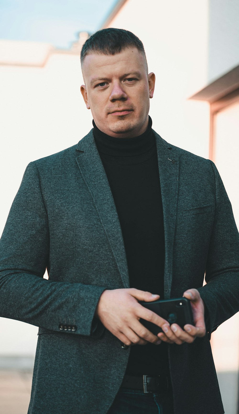 man in black suit holding black smartphone