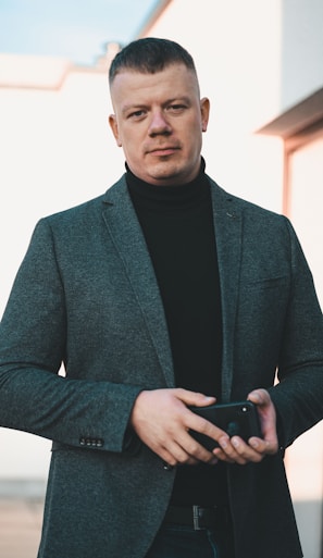 man in black suit holding black smartphone