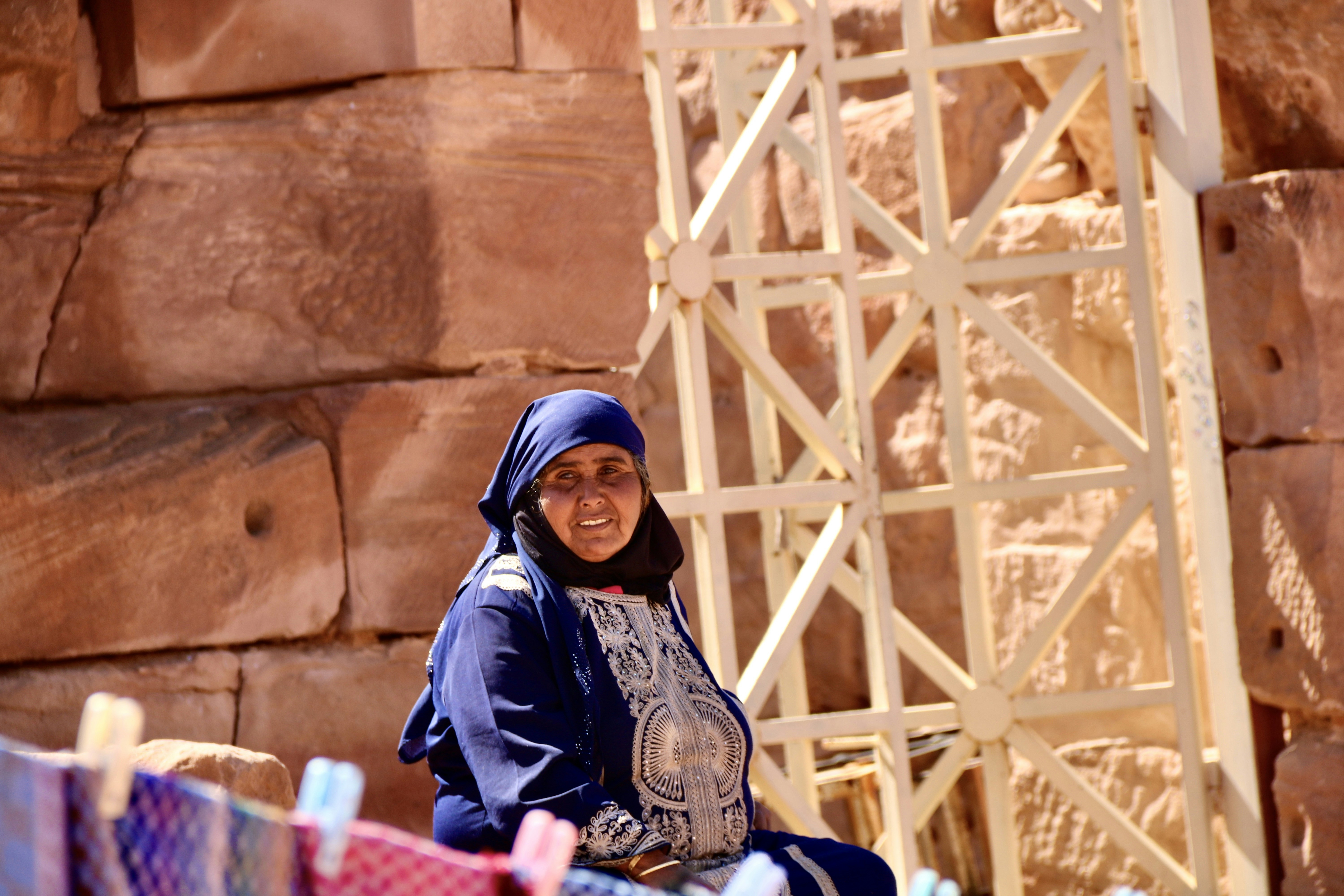 Woman in blue and white hijab sitting on brown wooden bench