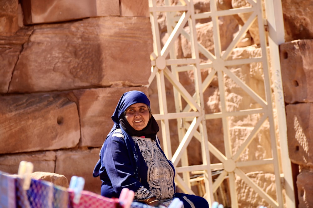 Femme en hijab bleu et blanc assise sur un banc en bois brun