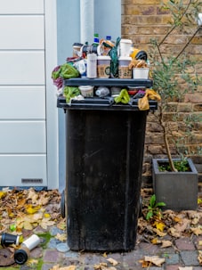 black trash bin with green leaves