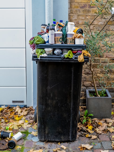 black trash bin with green leaves