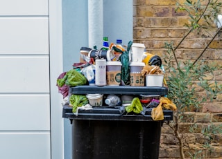 black trash bin with green leaves