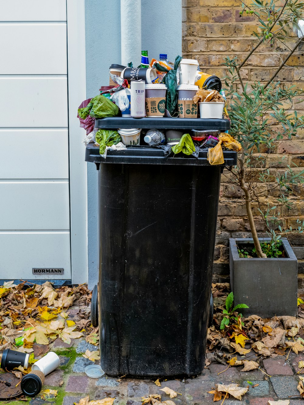 black trash bin with green leaves