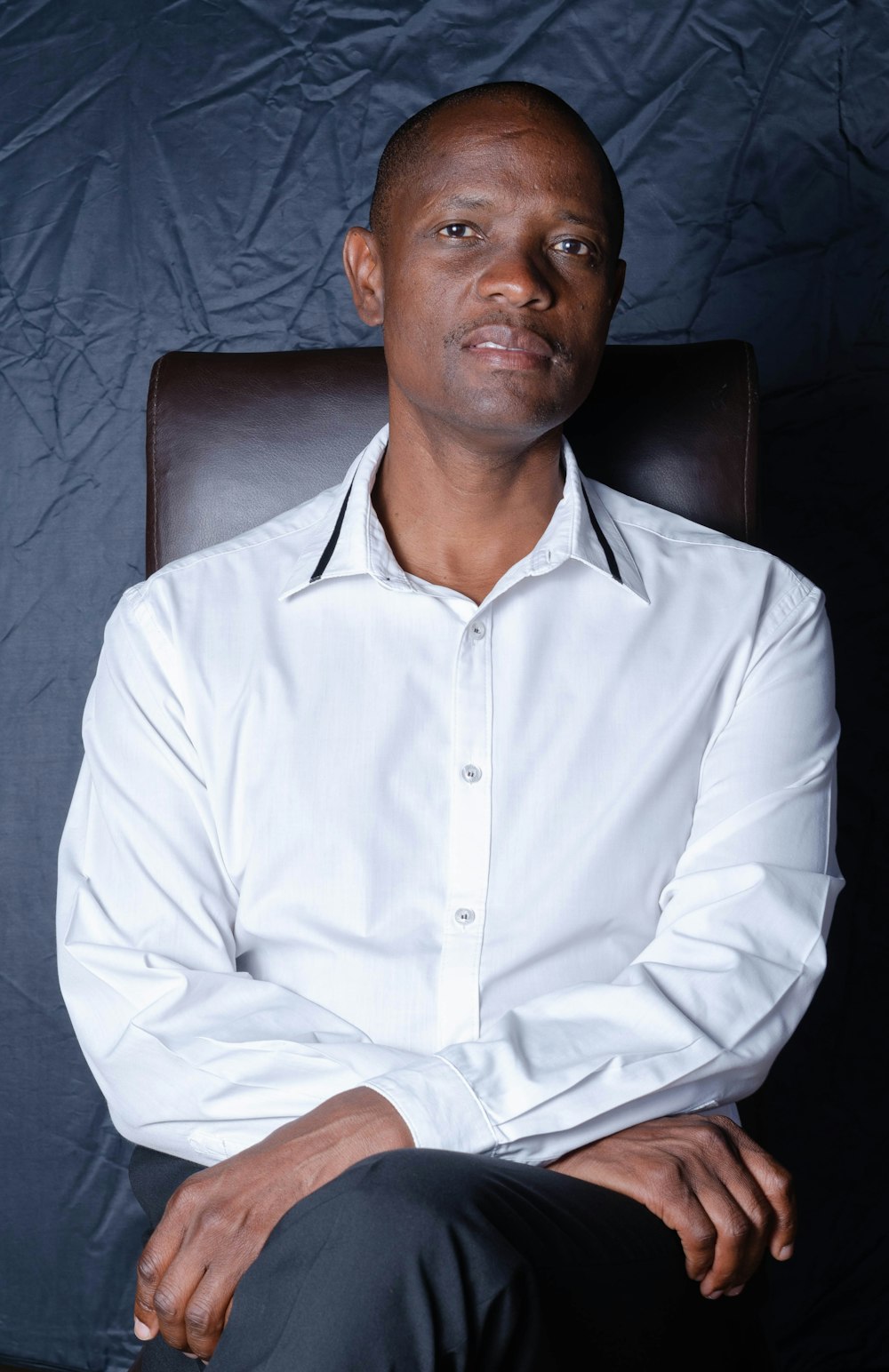 man in white dress shirt sitting on black leather chair