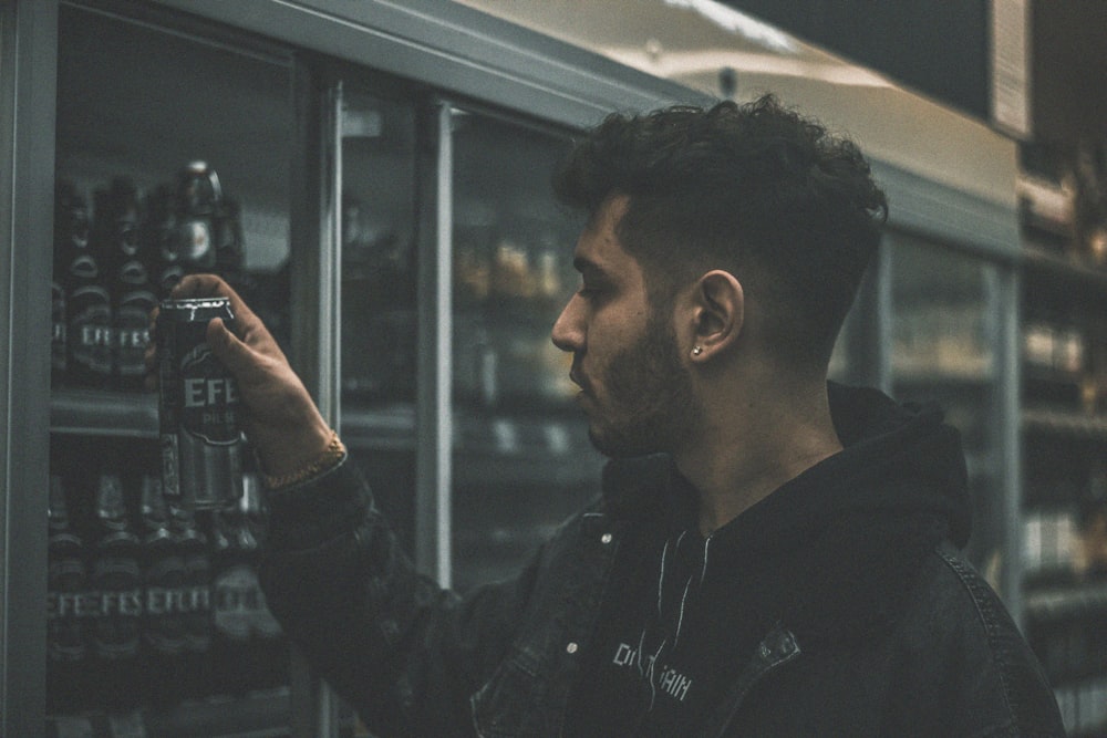 man in black jacket holding a glass bottle