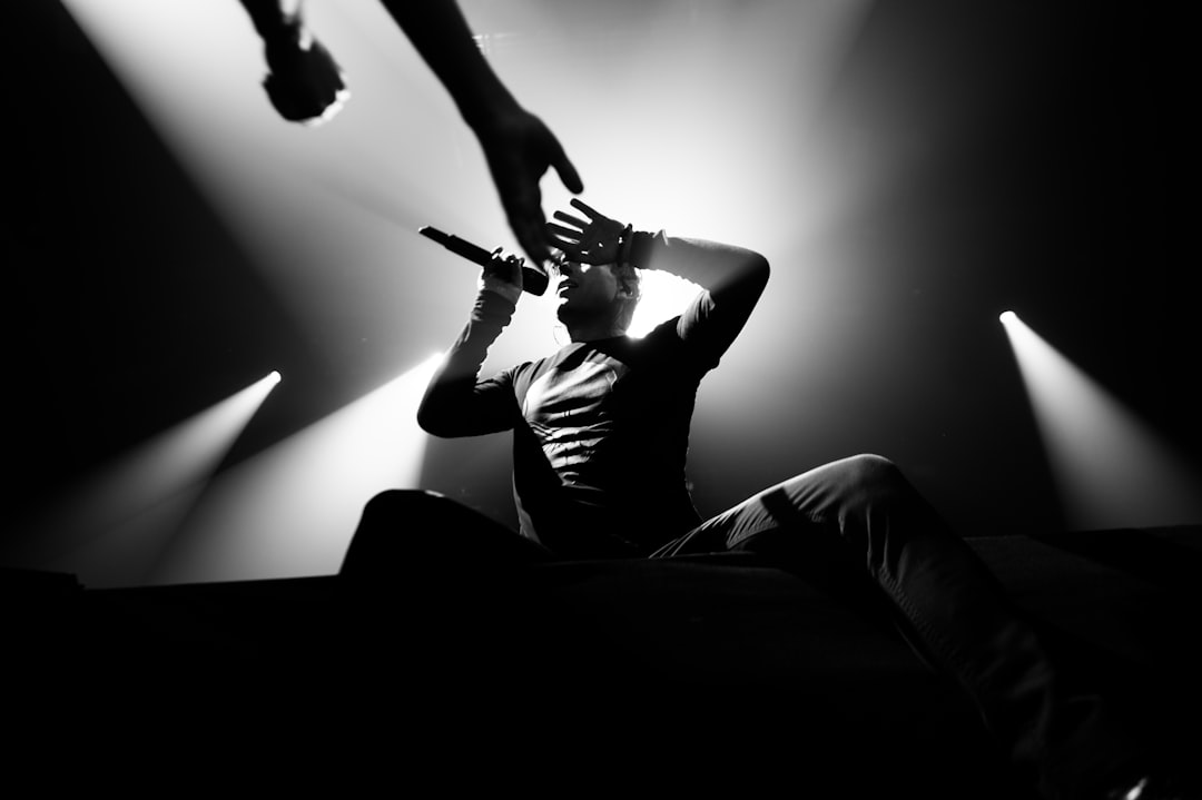 man in black t-shirt and black pants sitting on black sofa