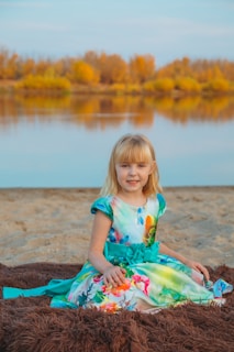 A sunny California beach scene with a teenage girl sitting on a colorful blanket, journaling her thoughts.