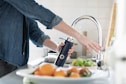 person in blue denim jacket holding stainless steel bottle