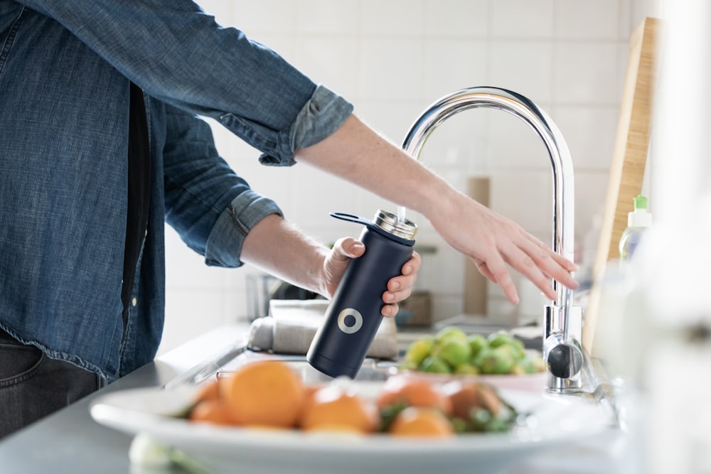 person in blue denim jacket holding stainless steel bottle