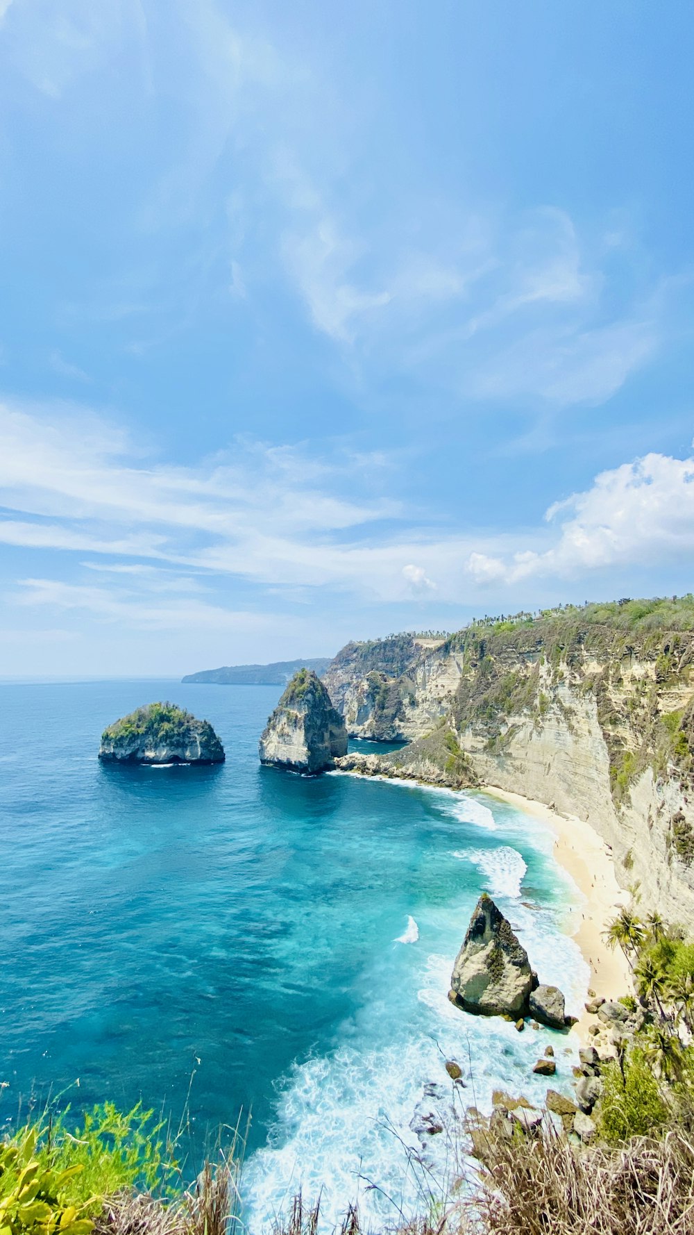 green and brown mountain beside blue sea under blue sky during daytime