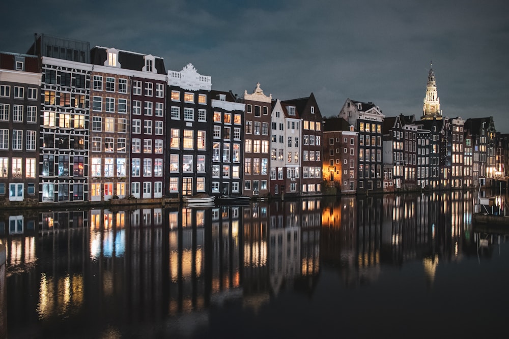 edificio in cemento marrone e bianco vicino allo specchio d'acqua durante la notte