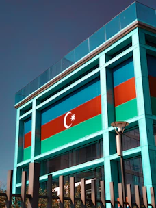 A professional signing business documents with the Azerbaijan flag in the background.