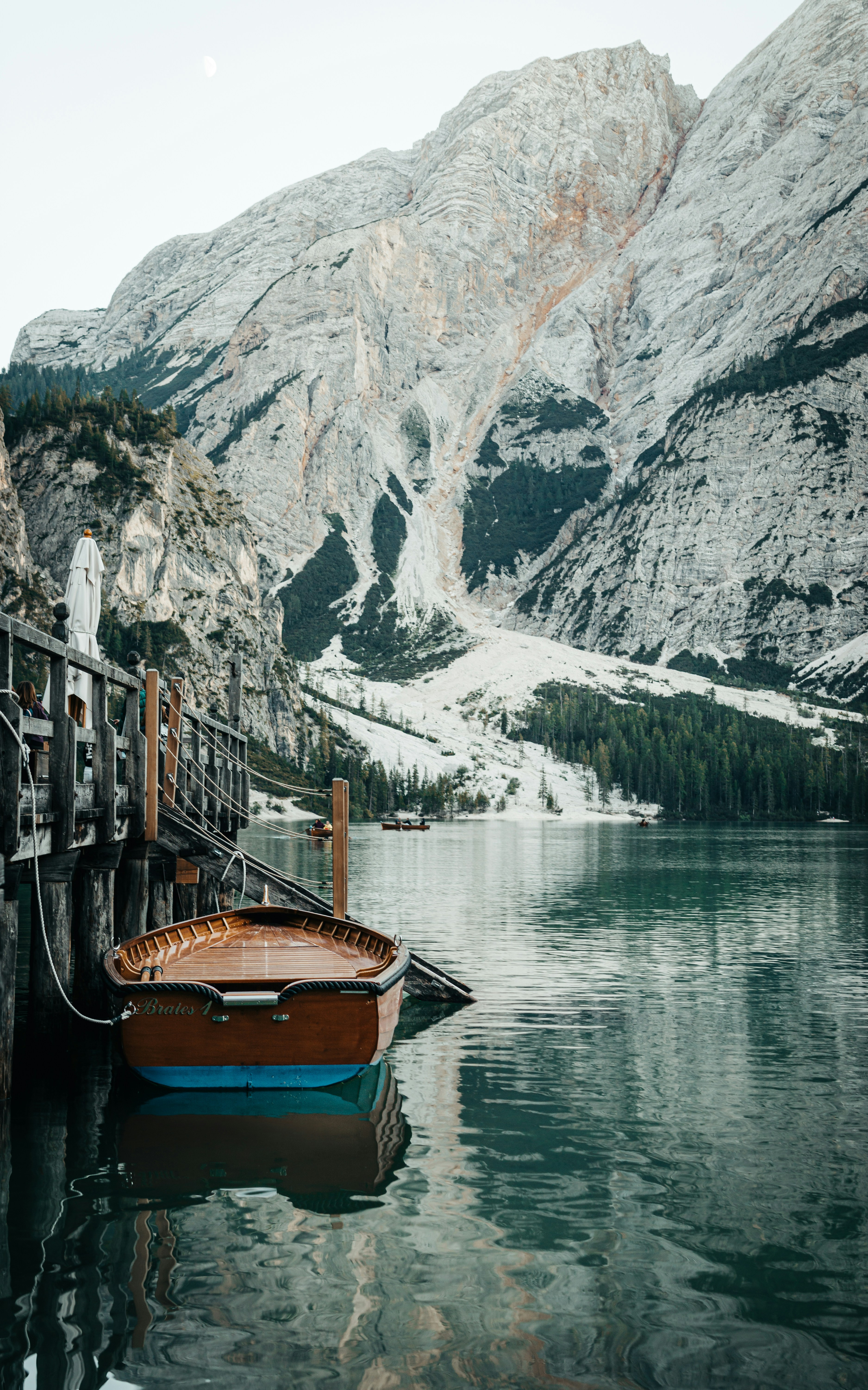 brown wooden boat on water near mountain during daytime