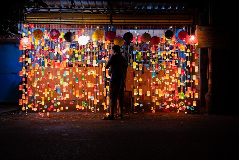 man in black jacket standing in front of red and yellow heart shaped wall decor