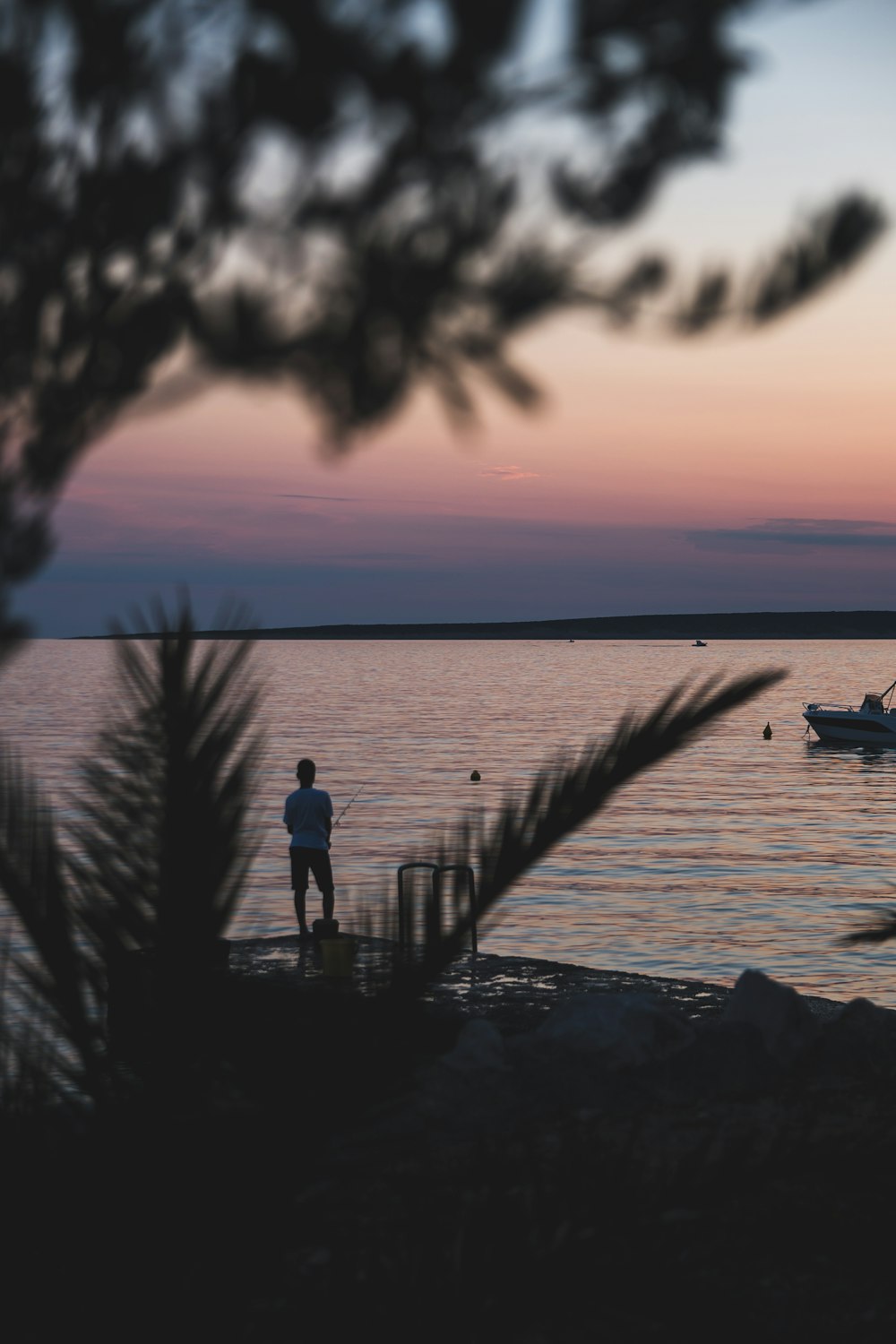 silhouette of man standing on dock during sunset