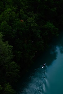 Kayaker paddling through the serene waters of Bariloche surrounded by lush green mountains.