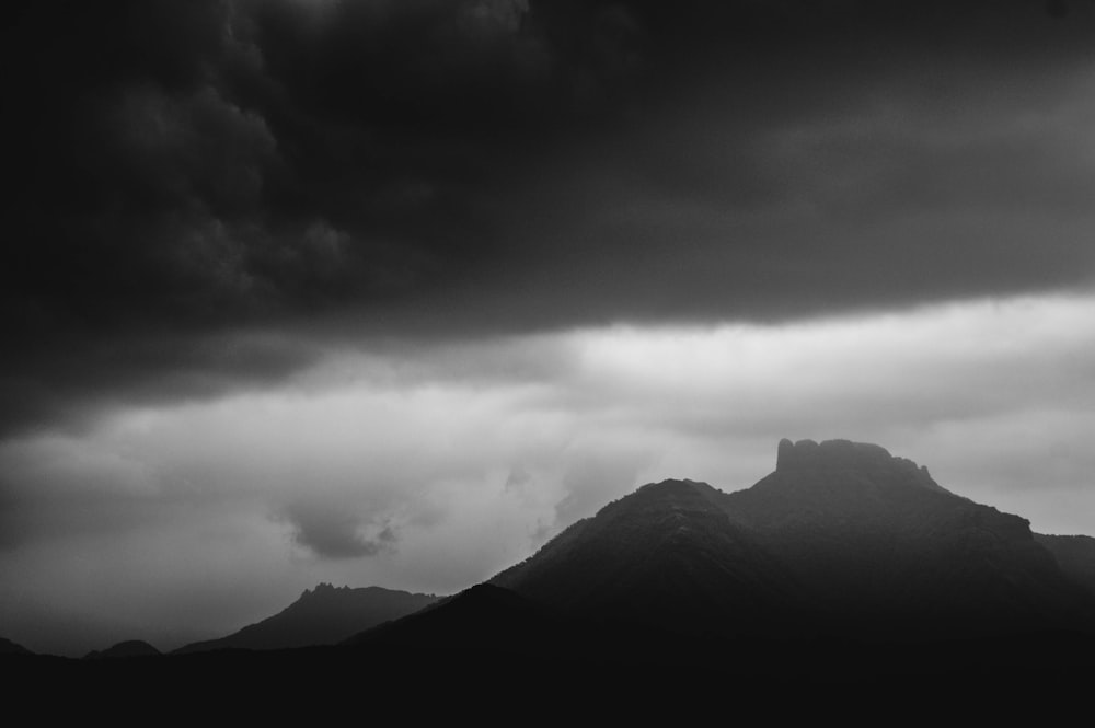 grayscale photo of mountain under cloudy sky