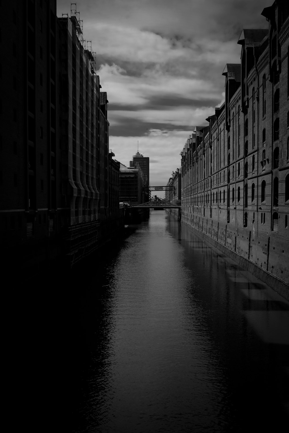 grayscale photo of river between buildings