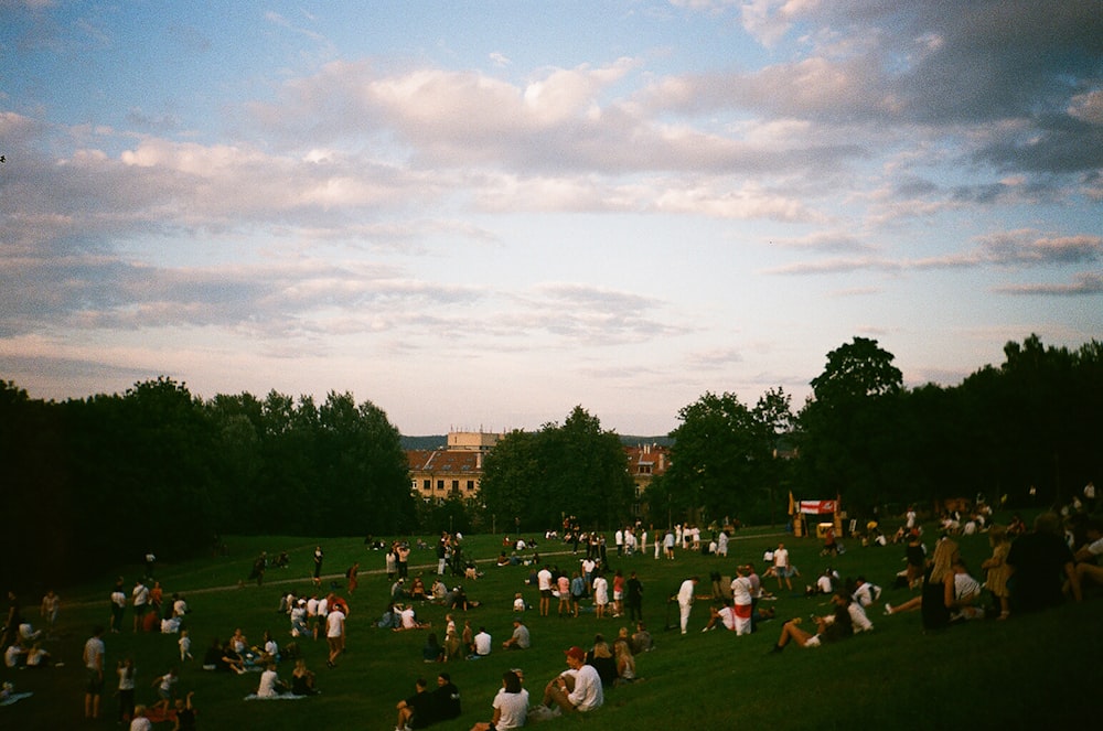 persone sedute sul campo di erba verde durante il giorno