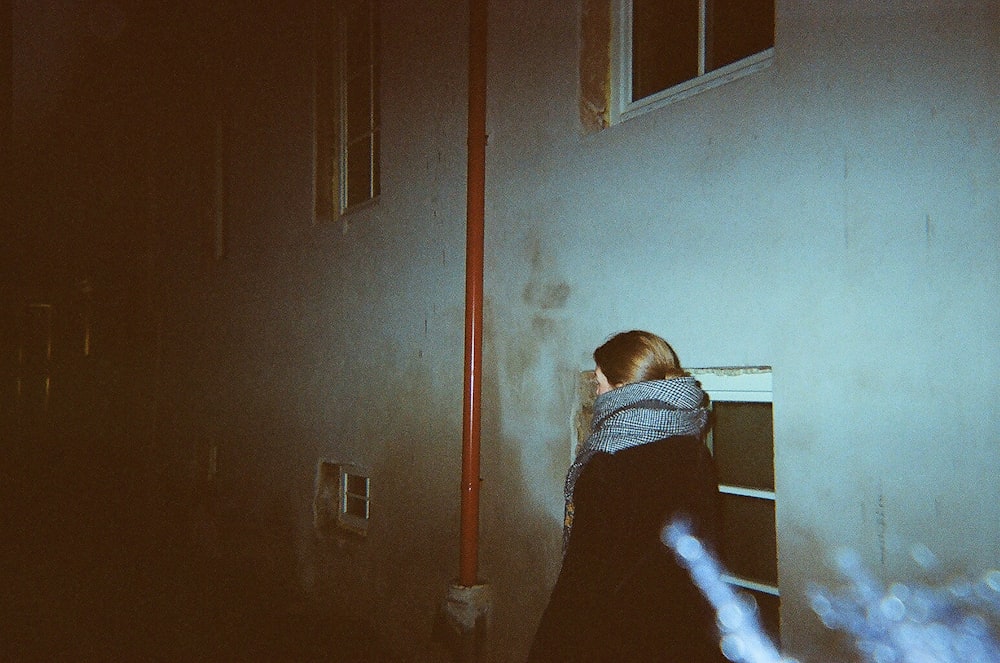 woman in black and white shirt standing near white wall