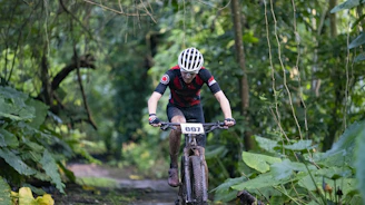 A cyclist wearing a bright helmet and gloves riding on a forest trail