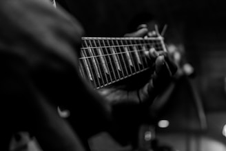 person playing guitar in grayscale photography