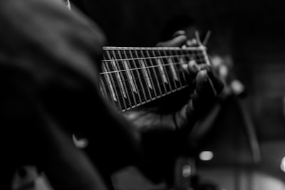 person playing guitar in grayscale photography