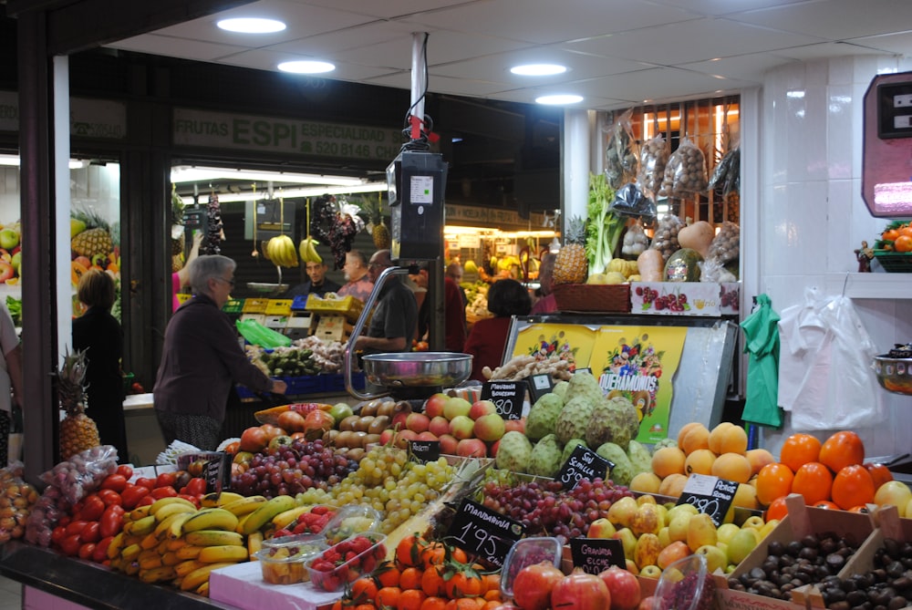 man in gray jacket standing near fruit stand