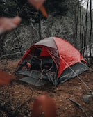 Float tent pitched on wet, muddy forest floor with morning dew.