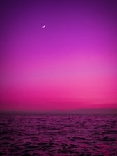 A glowing pastel neon moon intertwined with ocean waves under a starry sky.