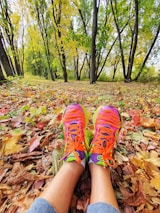 Close-up of running shoes on a rocky path surrounded by autumn leaves, symbolizing connection to nature.