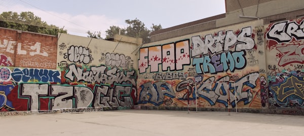 A courtyard with two walls, each completely-covered with graffiti tags.