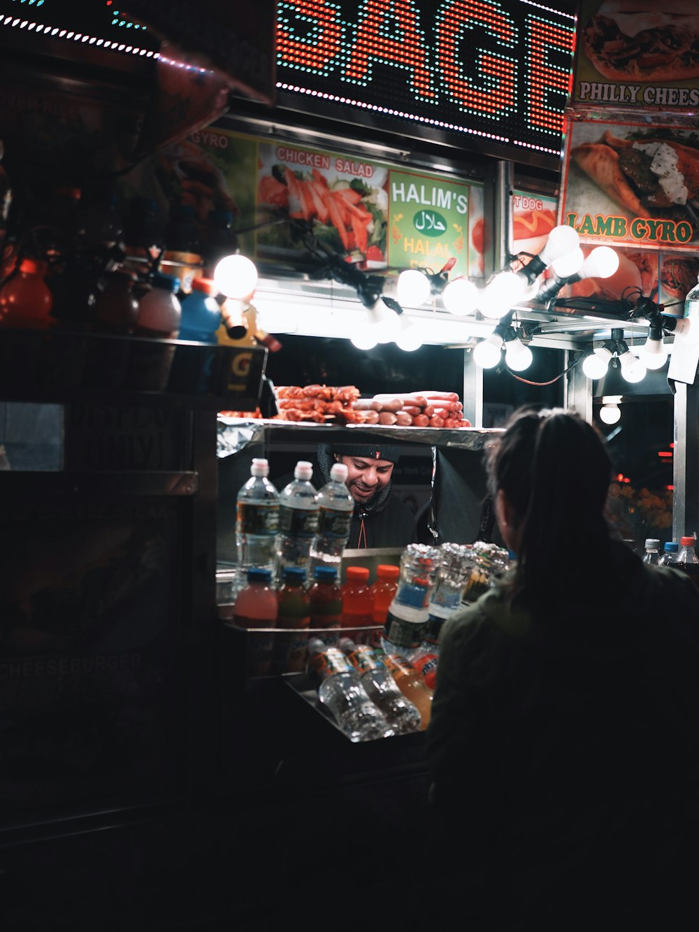 woman in black jacket standing in front of food display counter