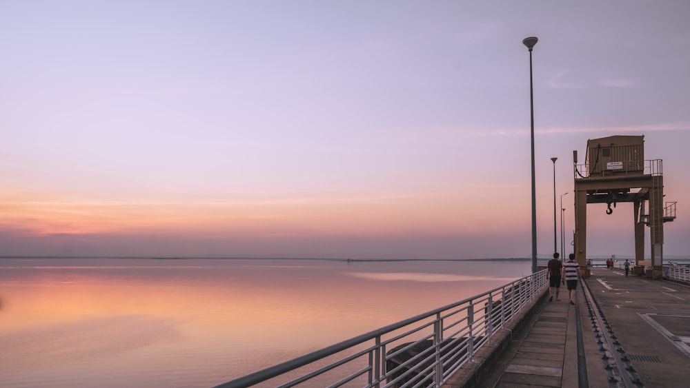 black metal railings on sea during sunset