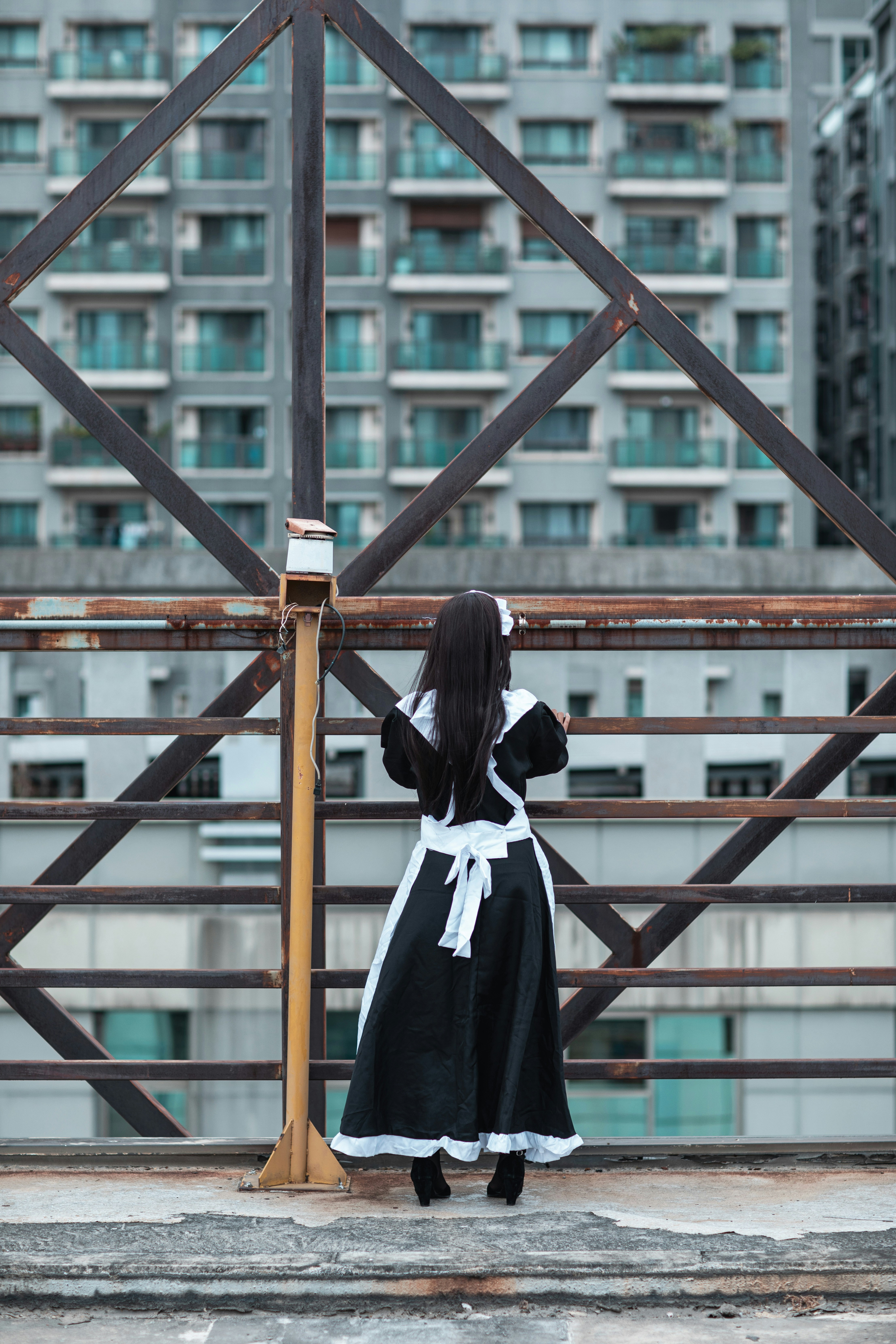 Wanita berseragam sekolah hitam putih berdiri di jembatan kayu coklat