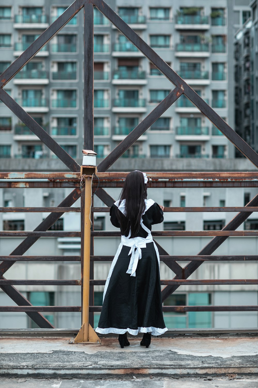 woman in black and white school uniform standing on brown wooden bridge
