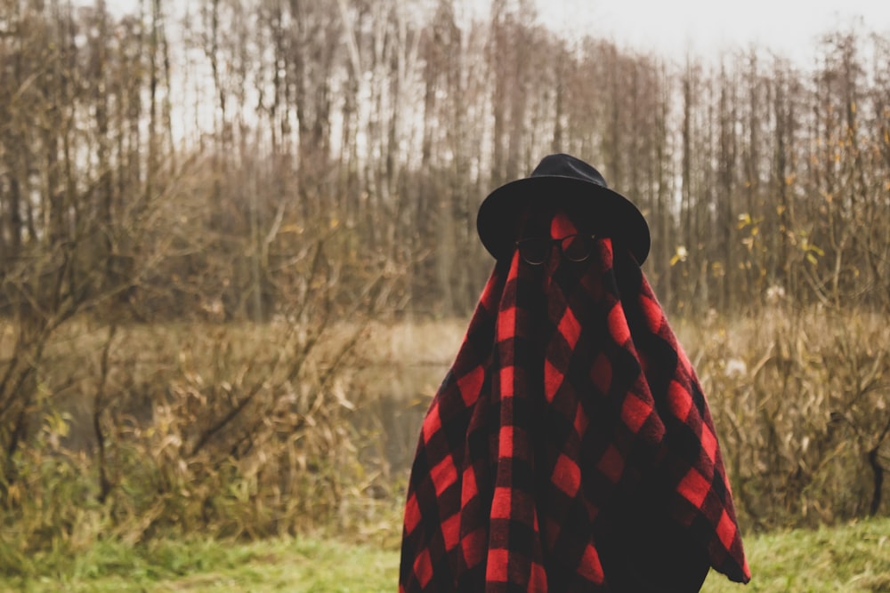 person in black and red checkered hoodie standing on green grass field during daytime