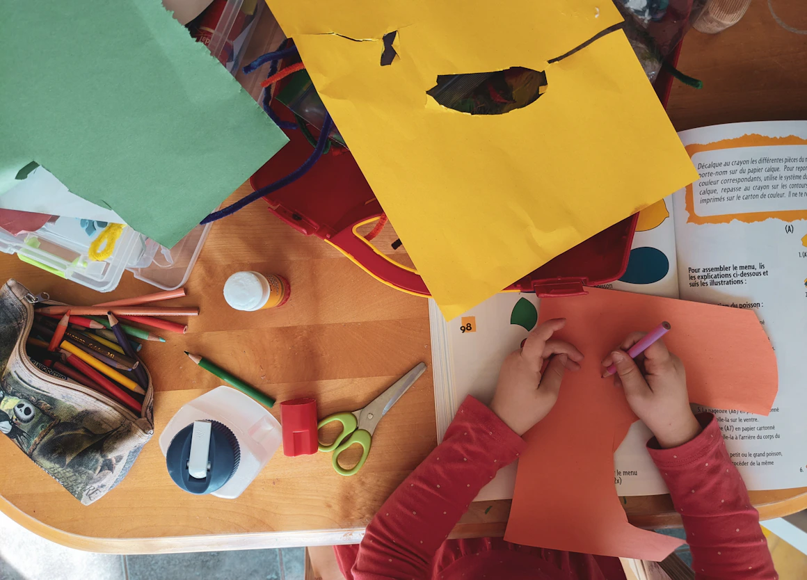 A child creating an art project at a table with real craft materials