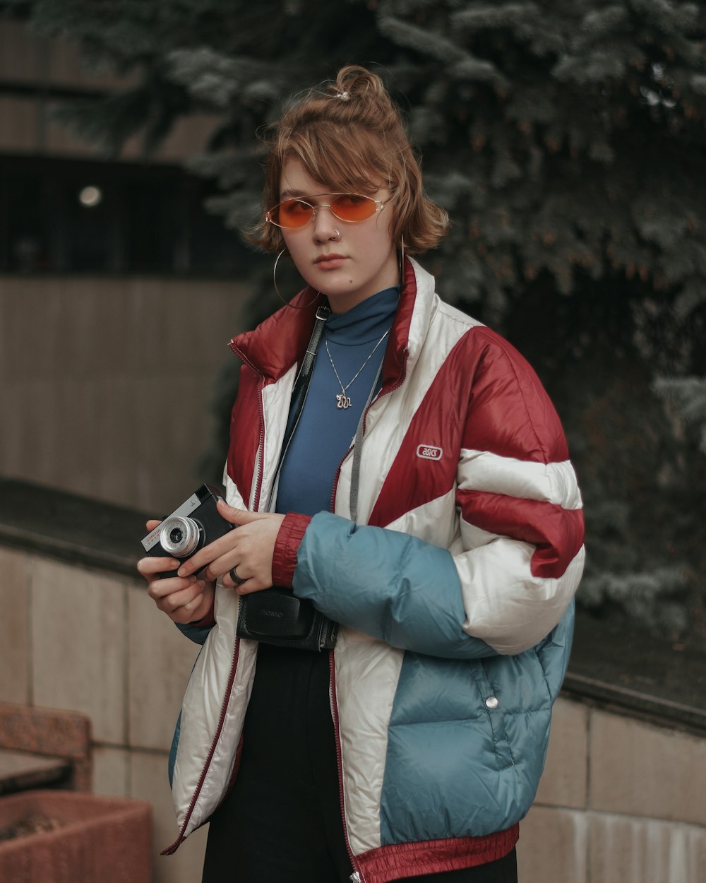 woman in blue jacket holding black camera