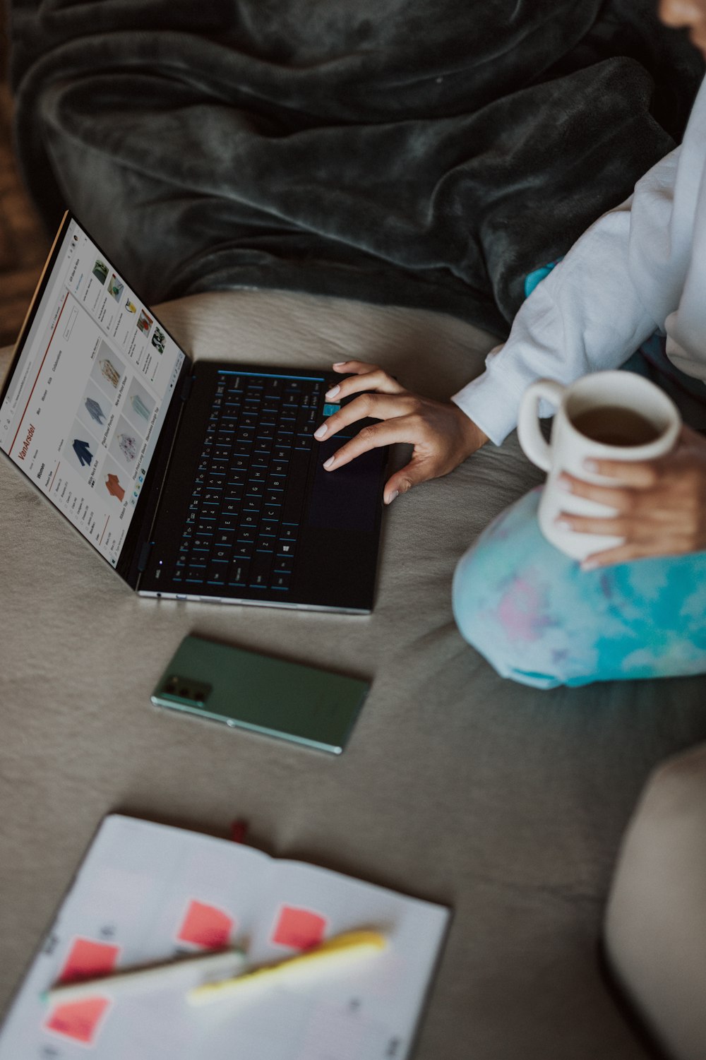 person in white and blue floral shirt holding black laptop computer