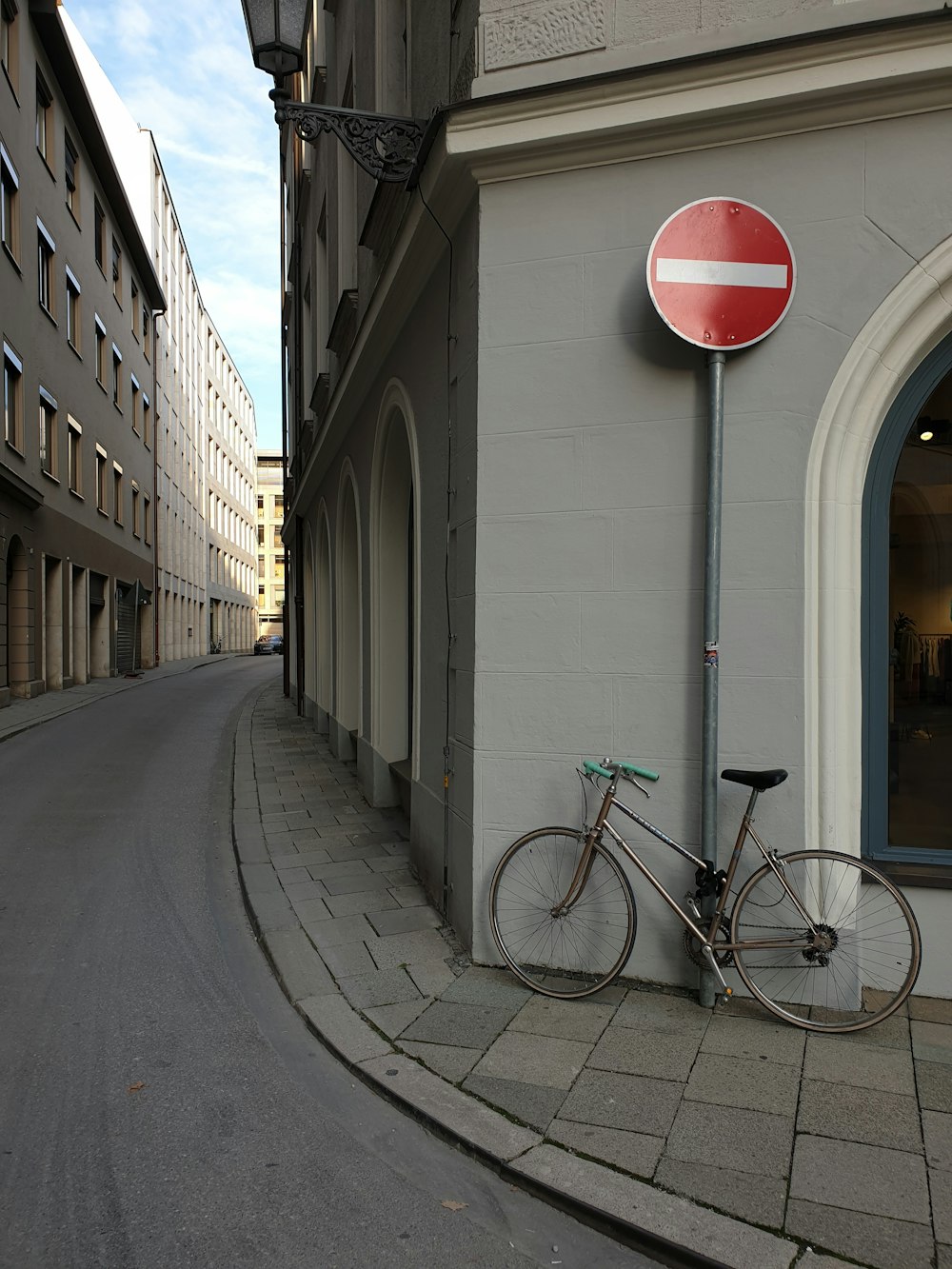 black and gray road bike parked beside white concrete building during daytime