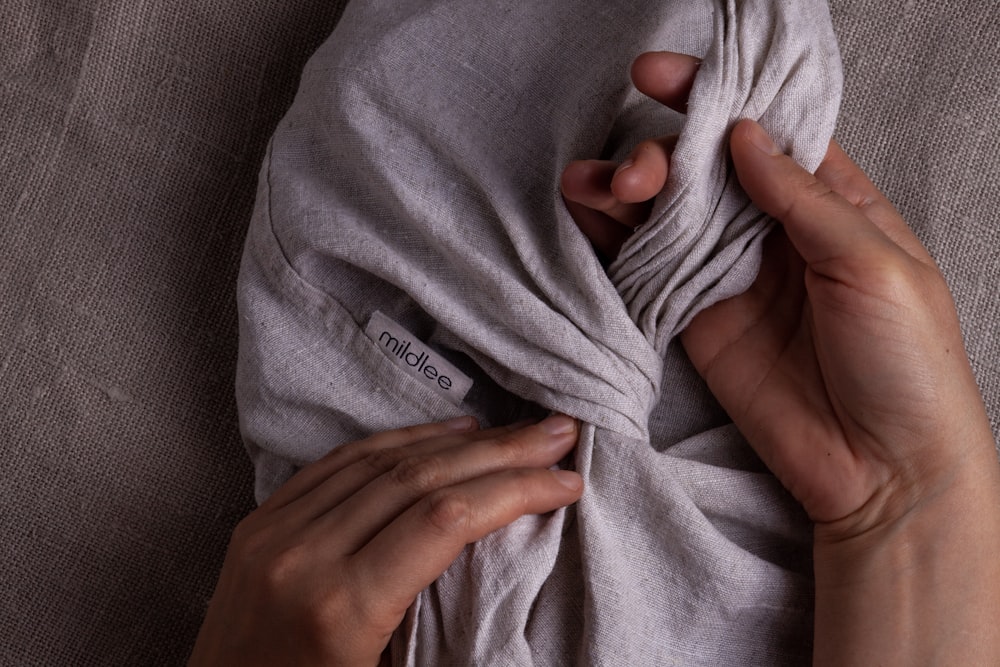 person holding gray textile on gray textile