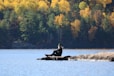 man in black jacket sitting on rock in the middle of the sea during daytime