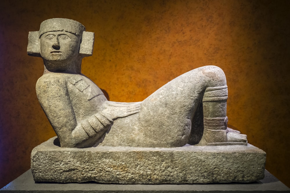 Estatua de hormigón gris del hombre sentado en el banco de hormigón gris