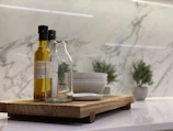 Artfully arranged trio of olive oil bottles with herbal infusions on a rustic wooden table.